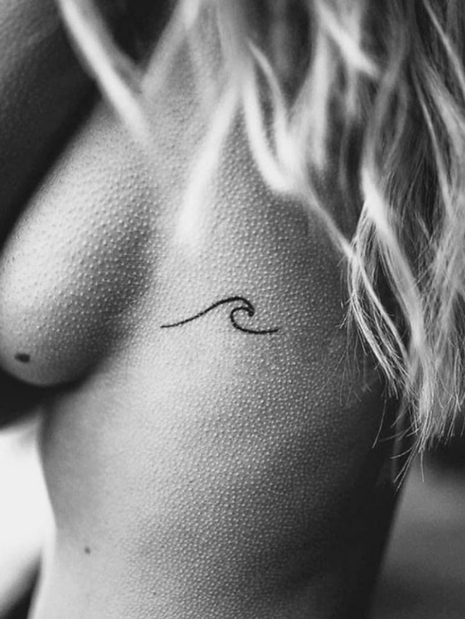 A finger tattoo of a minimalist wave design.