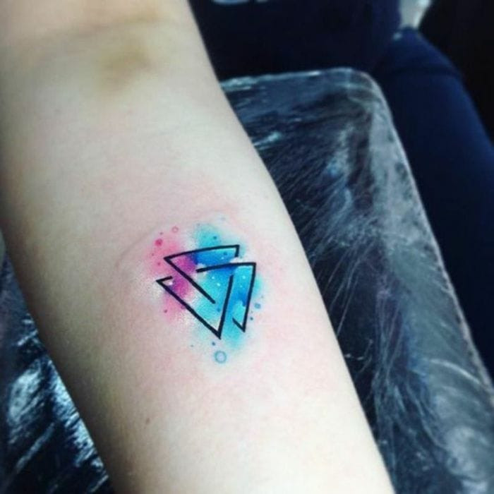 A hand featuring a Triquetra or Trinity Knot tattoo on the finger.