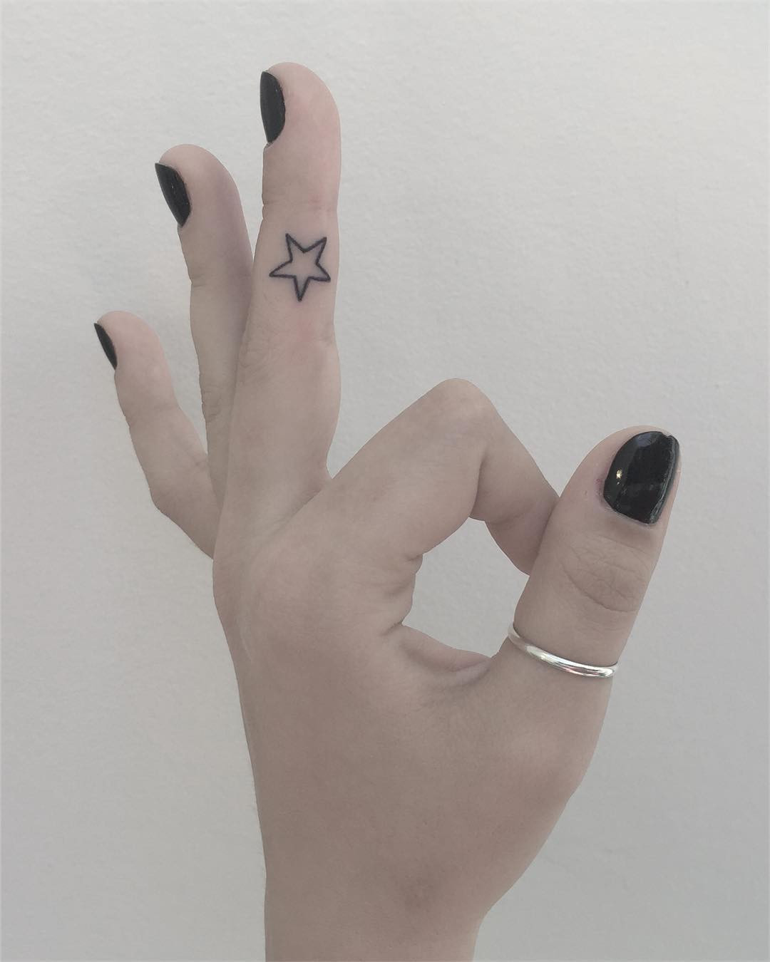 Finger with star outline tattoo