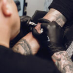 Tattoo artist working on a detailed sleeve tattoo, showcasing precision and artistry