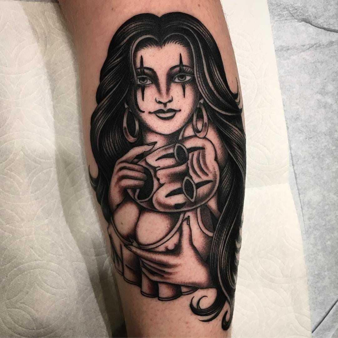 Tattoo by Paul Dobleman showcasing a Payasa mask, blending realism with surrealism, a hallmark of contemporary Chicano art.