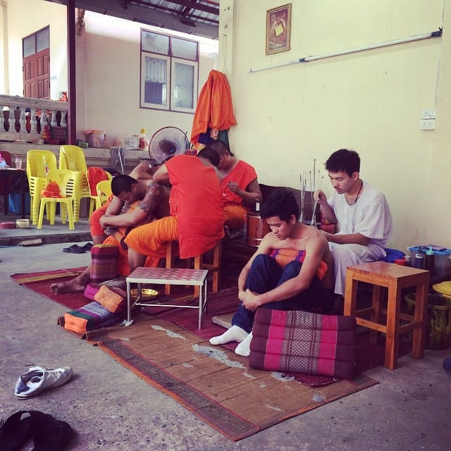 Wat Bang Phra monks tattooing a person's back