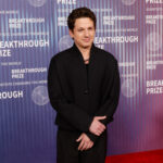 Charlie Puth's minimalist musical note tattoo, symbolizing his deep connection to music and identity as a singer-songwriter, visible on his right arm during a performance.