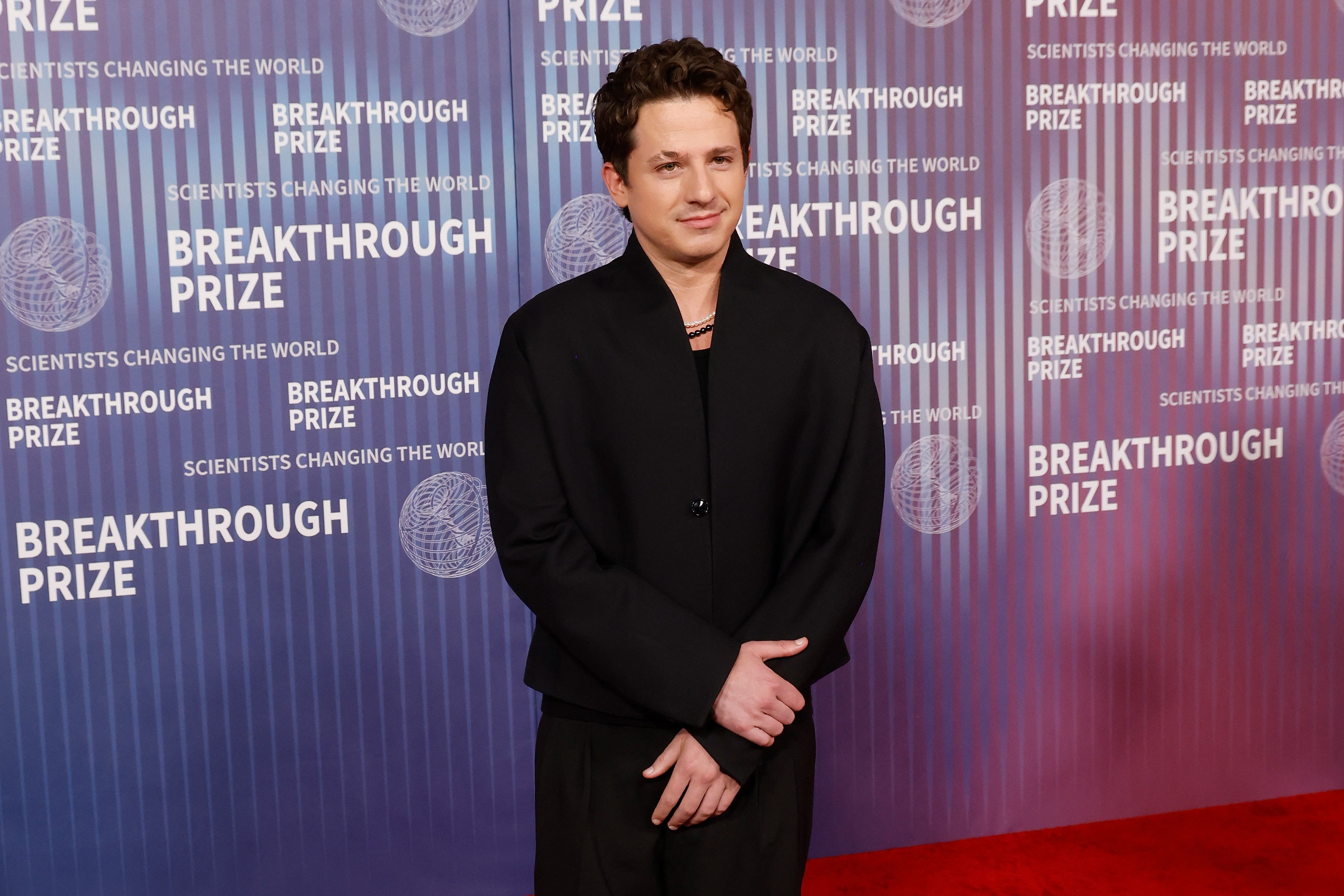 Charlie Puth's minimalist musical note tattoo, symbolizing his deep connection to music and identity as a singer-songwriter, visible on his right arm during a performance.