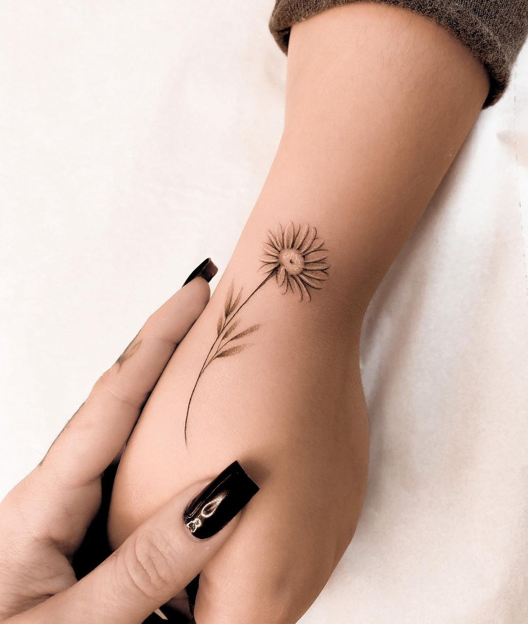 A daisy tattoo design on a woman's hand, showcasing a delicate and subtle design.