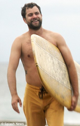 Joshua Jackson surfing, capturing his active lifestyle and the visibility of his arm tattoo under sunlight