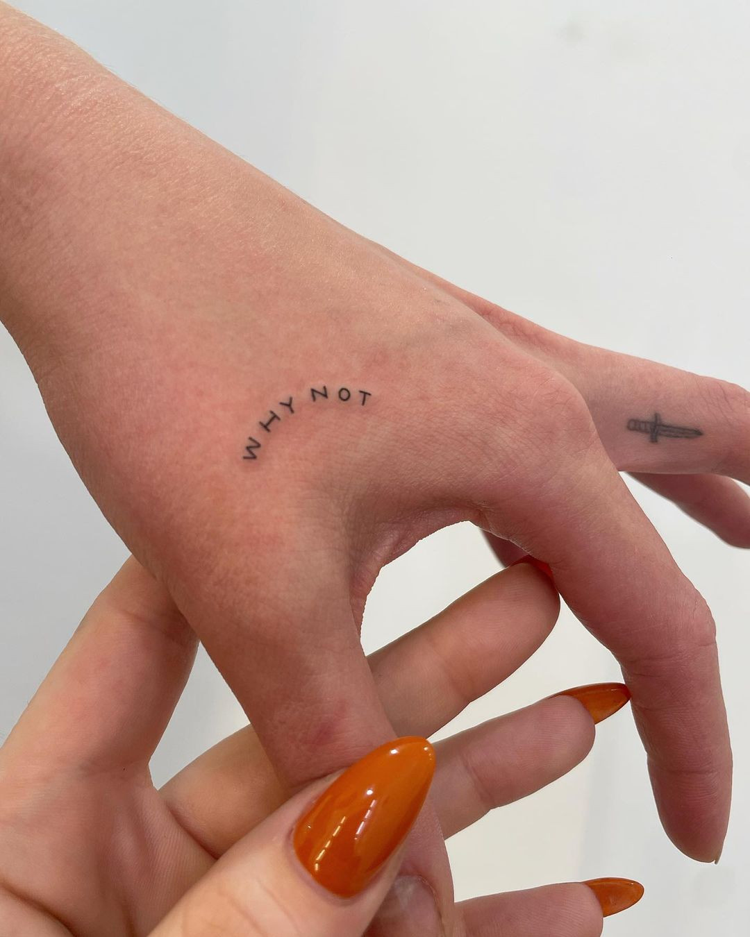 An inspirational 'why not' tattoo design on a woman's hand, serving as a daily reminder to embrace opportunities.