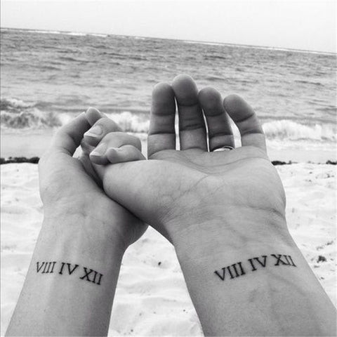 Roman numeral couple tattoos on wrists symbolizing a shared date