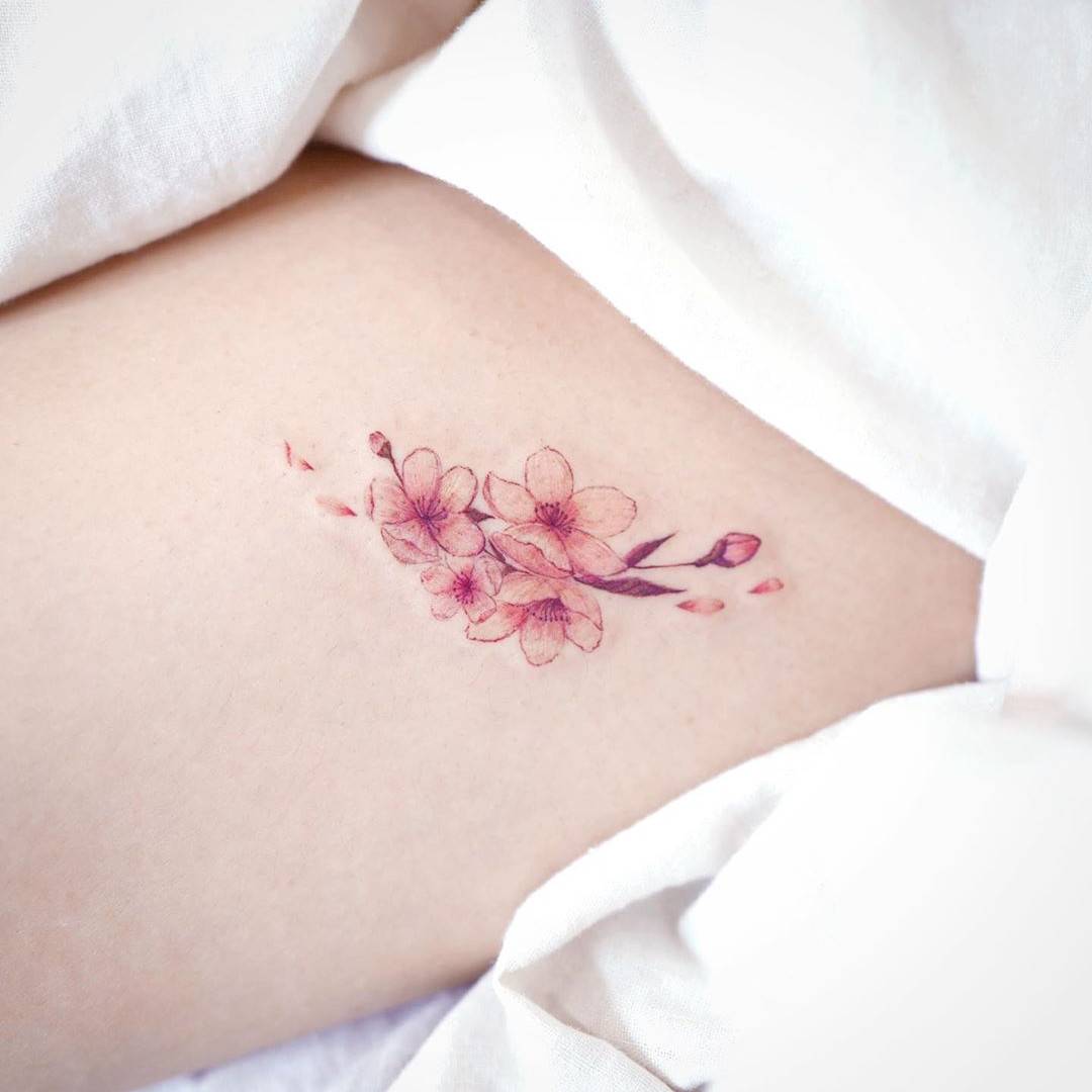 An intricate and colorful Japanese cherry blossom tattoo designed as a full sleeve on a person's arm.