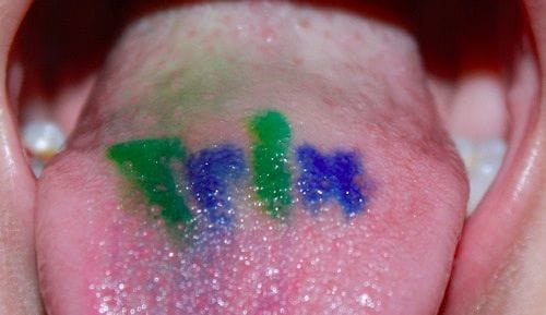 Someone rinsing their mouth with mouthwash as part of tongue tattoo aftercare