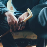 Man Sitting With Cane Old Hat White