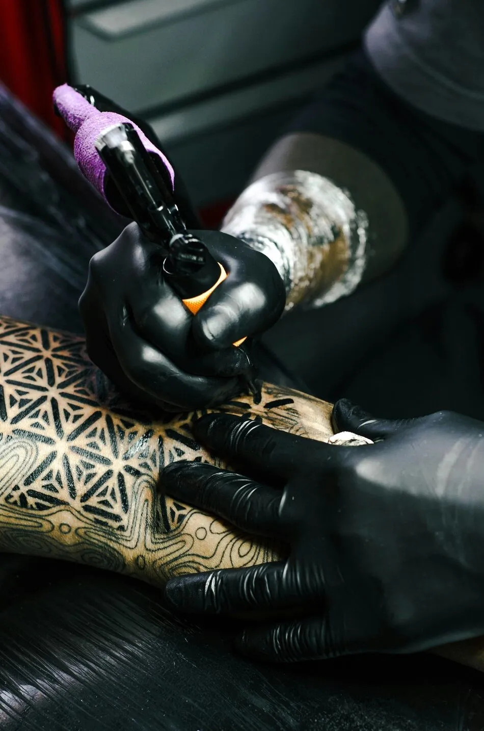 A tattoo artist making a tattoo to a client.
