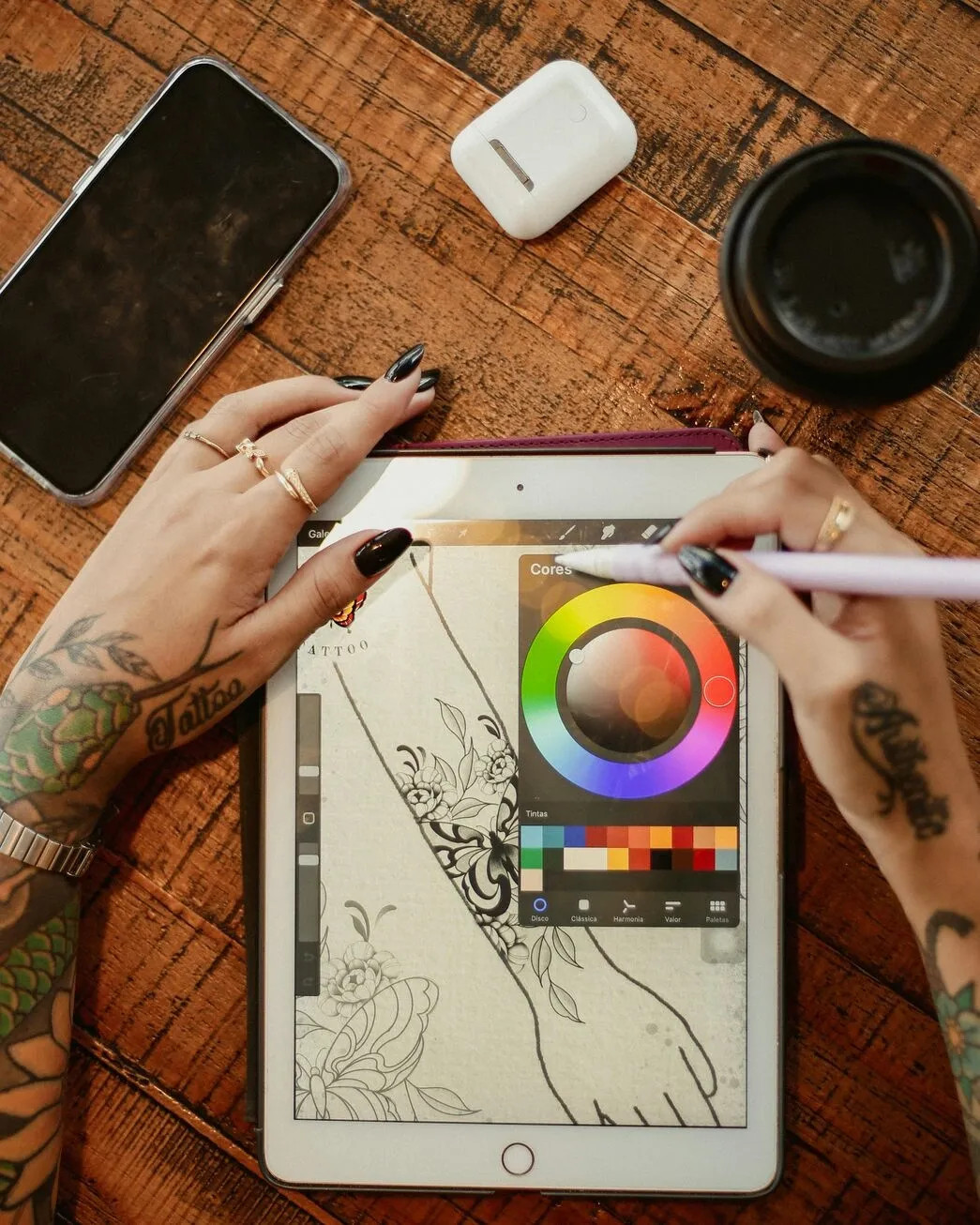 A tattoo artist drawing a design on a tablet.