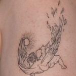 Simple black outline tattoo on the arm depicting a minimalist geometric shape.