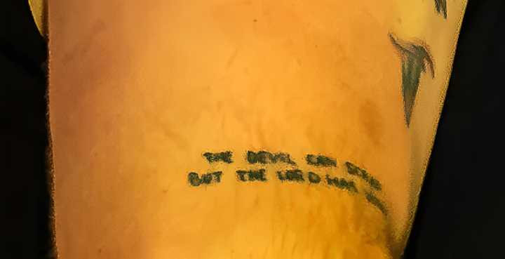Zach Bryan performing, displaying his &quot;The devil can scrap but the Lord has won&quot; tattoo.