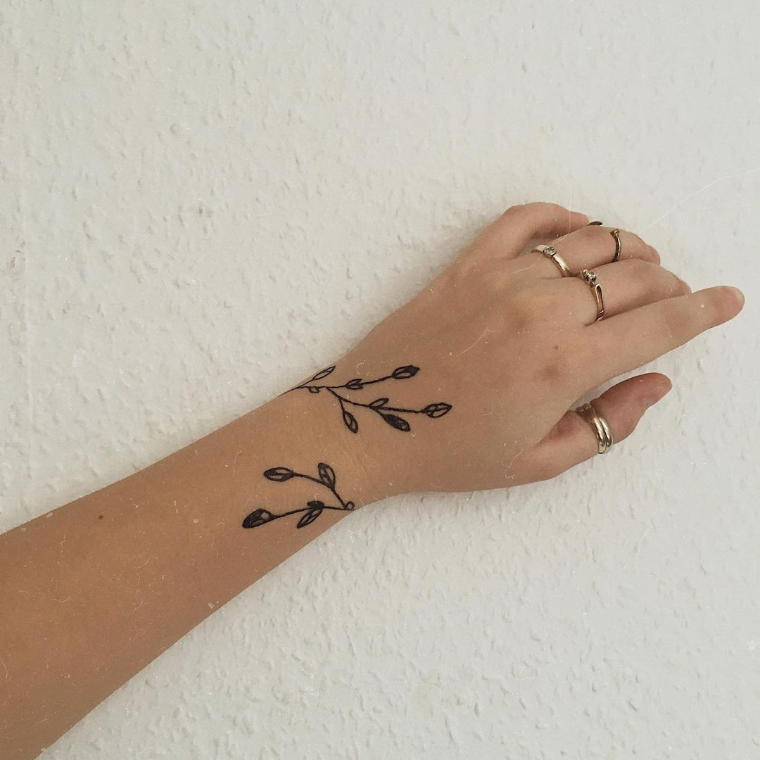 A leaf around arm tattoo design that gives the illusion of a bracelet, adding a unique and stylish touch.