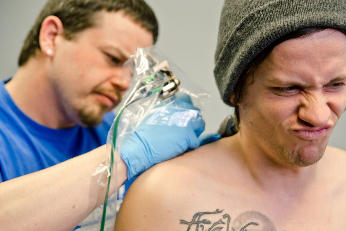 A person experiencing pain while getting a permanent tattoo, highlighting the comfort of temporary alternatives