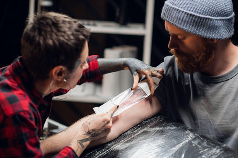 A tattoo artist bandages the young man