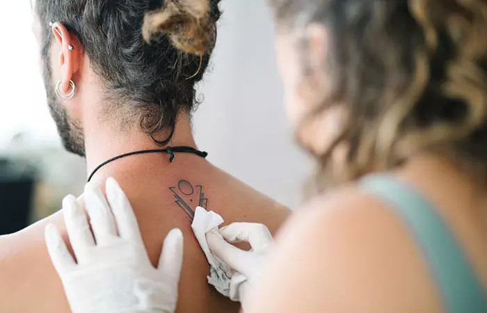 Tattoo artist carefully cleaning a new tattoo