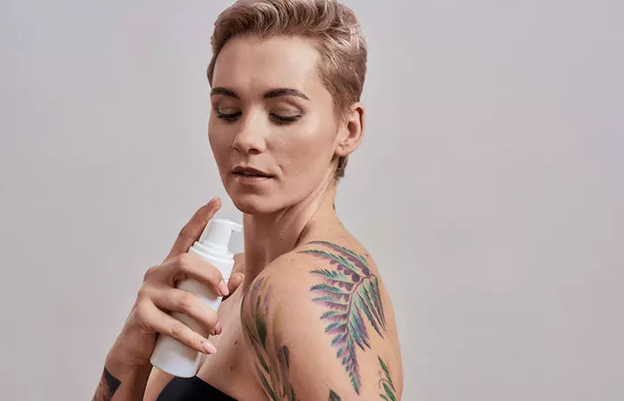 Woman applying moisturizer to watercolor tattoo