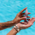 Woman holding vitamin E oil with arm tattoo