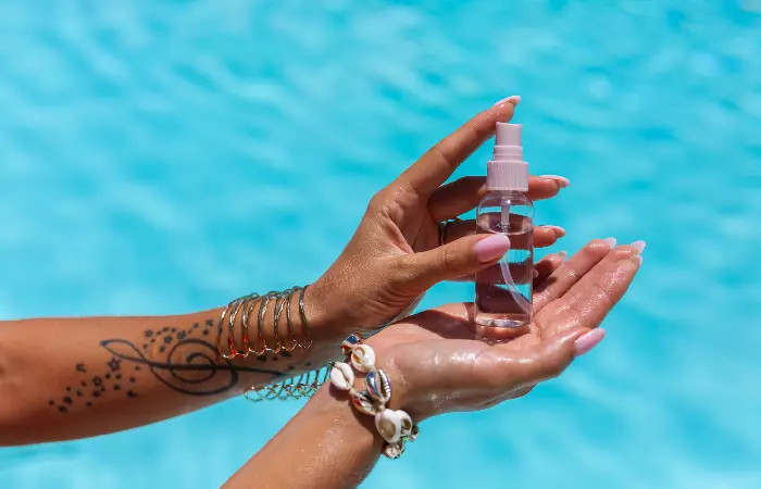 Woman holding vitamin E oil with arm tattoo