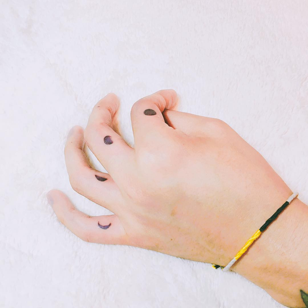A moon phase tattoo on a woman's fingers, symbolizing ever-changing life.