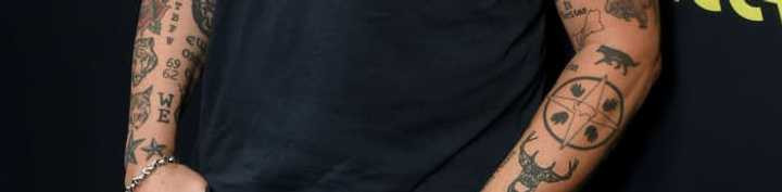 Titus Welliver's star sigil tattoo surrounded by footprints on his left forearm