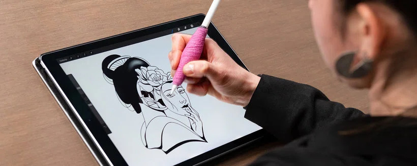 Close-up of a person using a digital drawing tablet with a stylus to create a tattoo design.