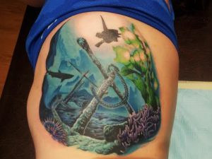 A tube of A&D ointment lying next to a freshly done arm tattoo, emphasizing the connection between aftercare and vibrant tattoo art