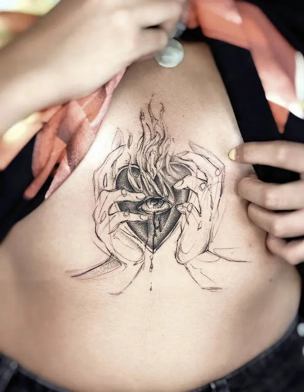 Burning sacred heart underboob tattoo symbolizing love.