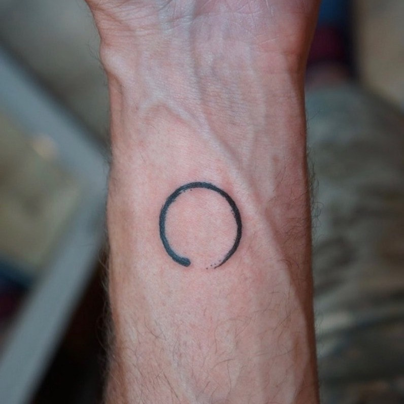 A finger tattoo featuring an Enso circle.