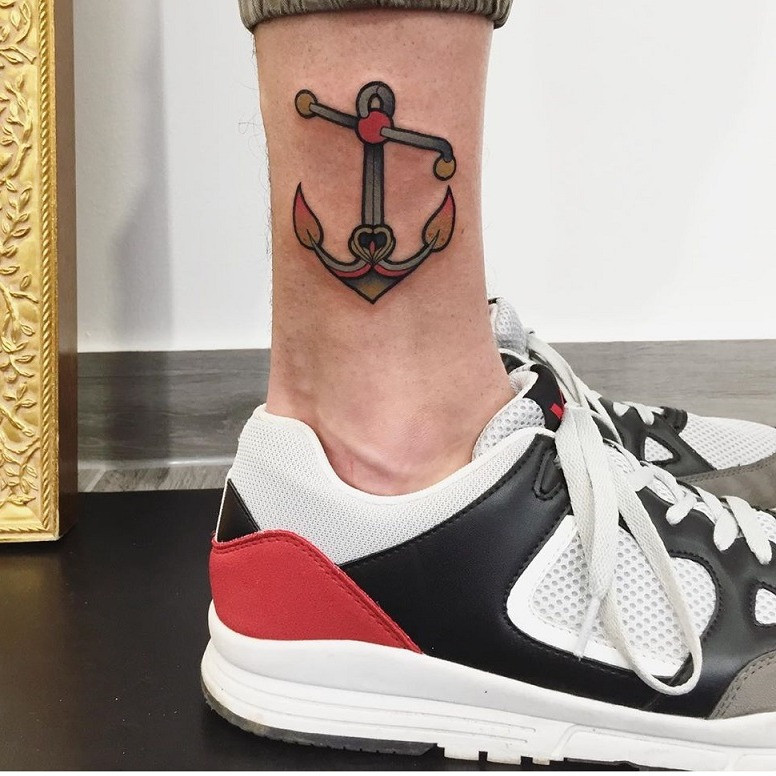 A finger tattoo of a small, minimalist anchor.