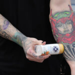 A person helping to heal their tattoo with Sanibalm.