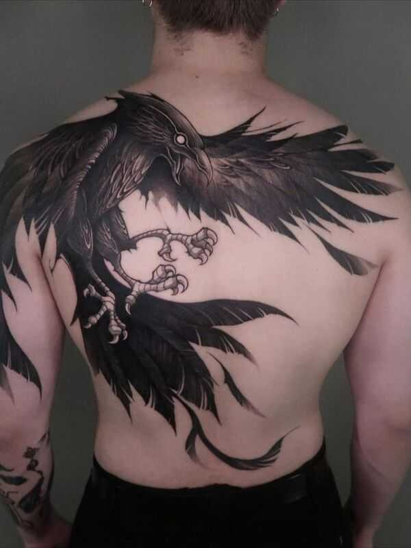 A crow tattoo design placed on the back, showcasing the bird's wings spanning across the shoulder blades