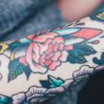 Dagger tattoo with roses and skull, symbolizing life, death, and beauty.