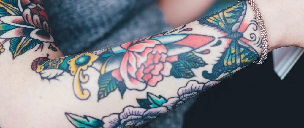 Dagger tattoo with roses and skull, symbolizing life, death, and beauty.