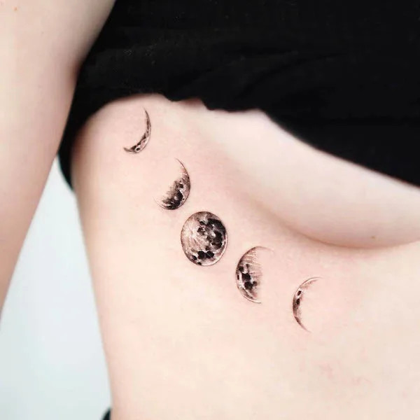 Detailed moon underboob tattoo positioned on the side.