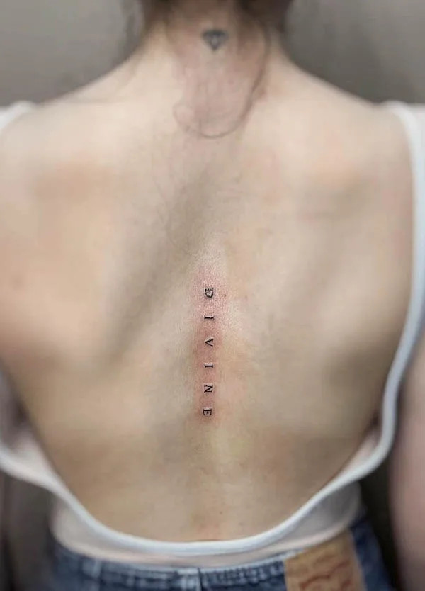 Simple spine tattoo featuring the word &quot;Divine&quot; vertically aligned, inked by @555jennariel
