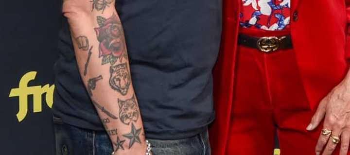 Titus Welliver's arm tattoo featuring a fist, stick, revolver, and knife