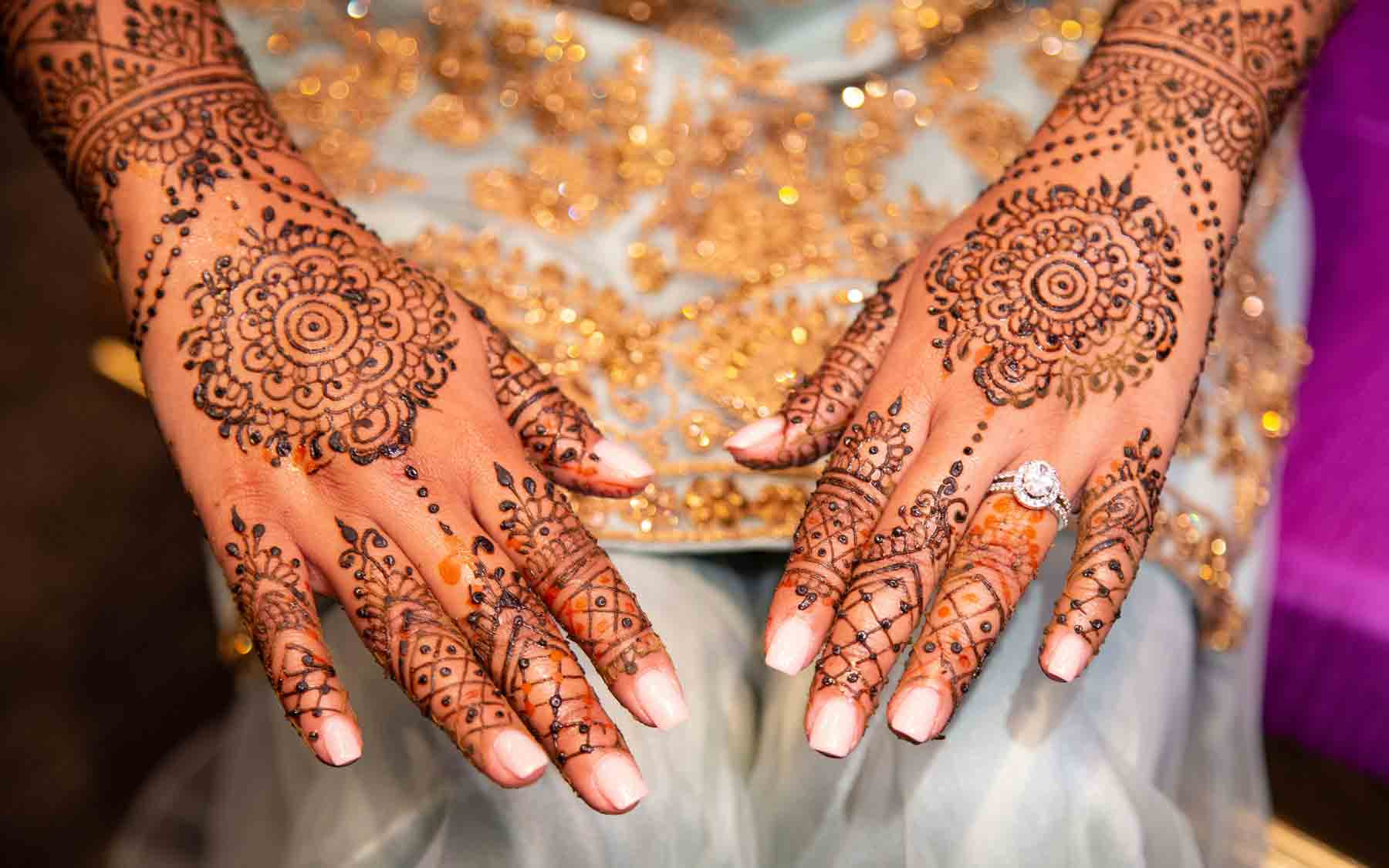 A bride displaying henna art on her hands and arms.