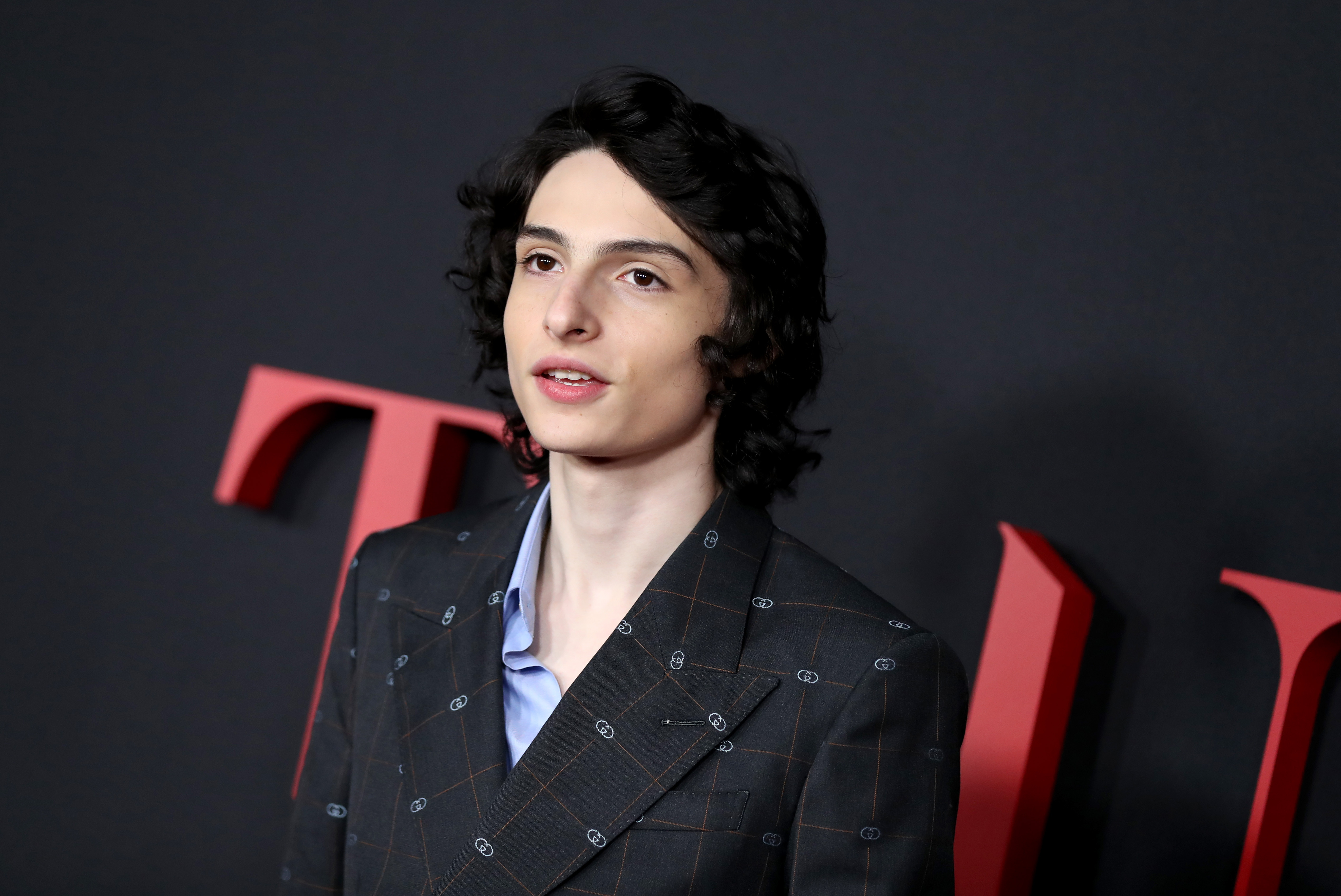 Finn Wolfhard's potential shoulder tattoo, as captured in a photoshoot, igniting fan speculation about his body art