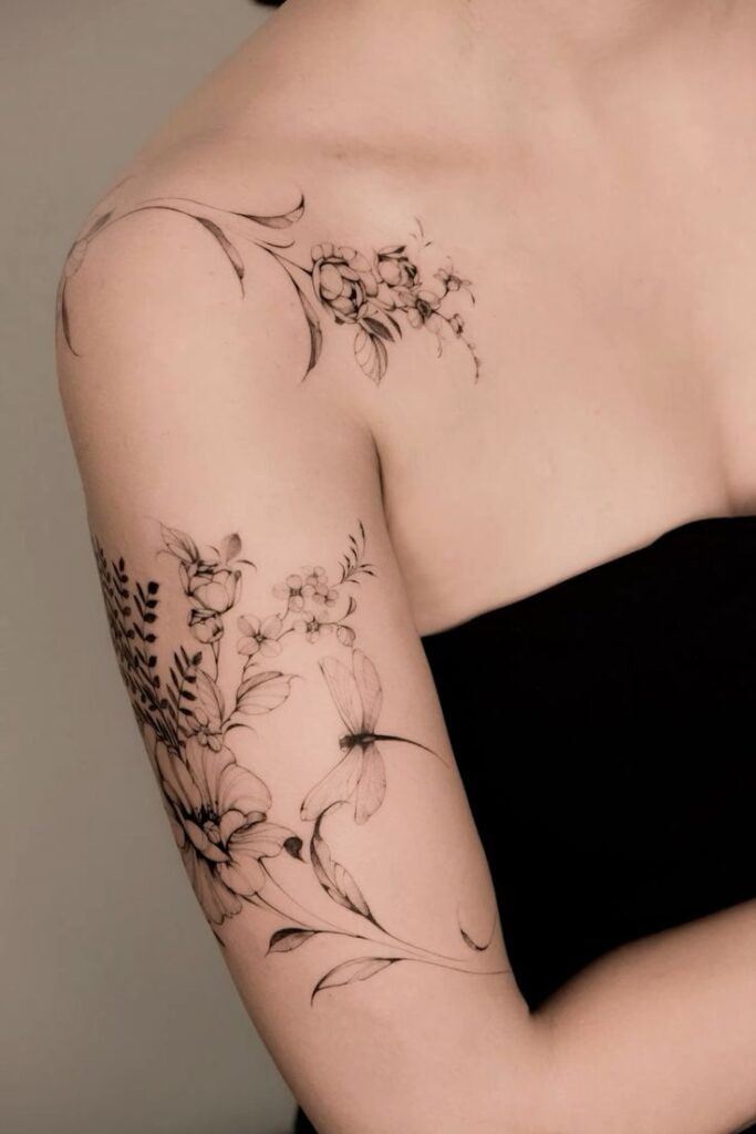 Delicate floral shoulder tattoo with intricate flowers and dragonfly design on a person