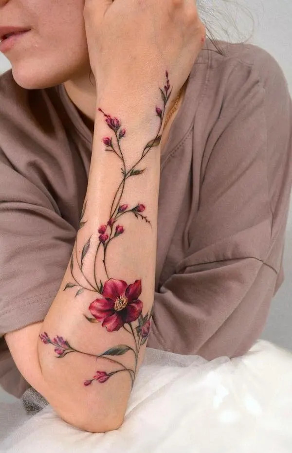 Elegant floral upper arm tattoo featuring delicate blossoms and green leaves