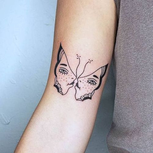 Two intertwined faces forming the Gemini symbol on the shoulder