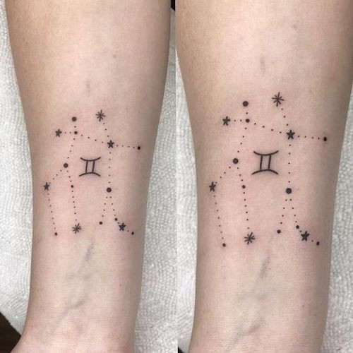 Detailed Gemini glyph tattoo with floral elements on the upper back