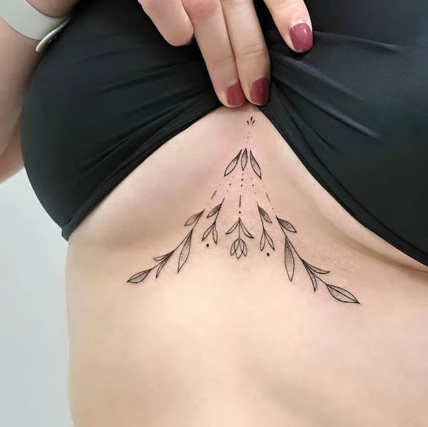 Geometric flower underboob tattoo blending natural forms with structured design.