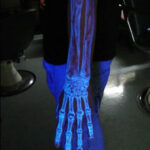 Glow in the dark tattoo of planets on arm with blue and green hues