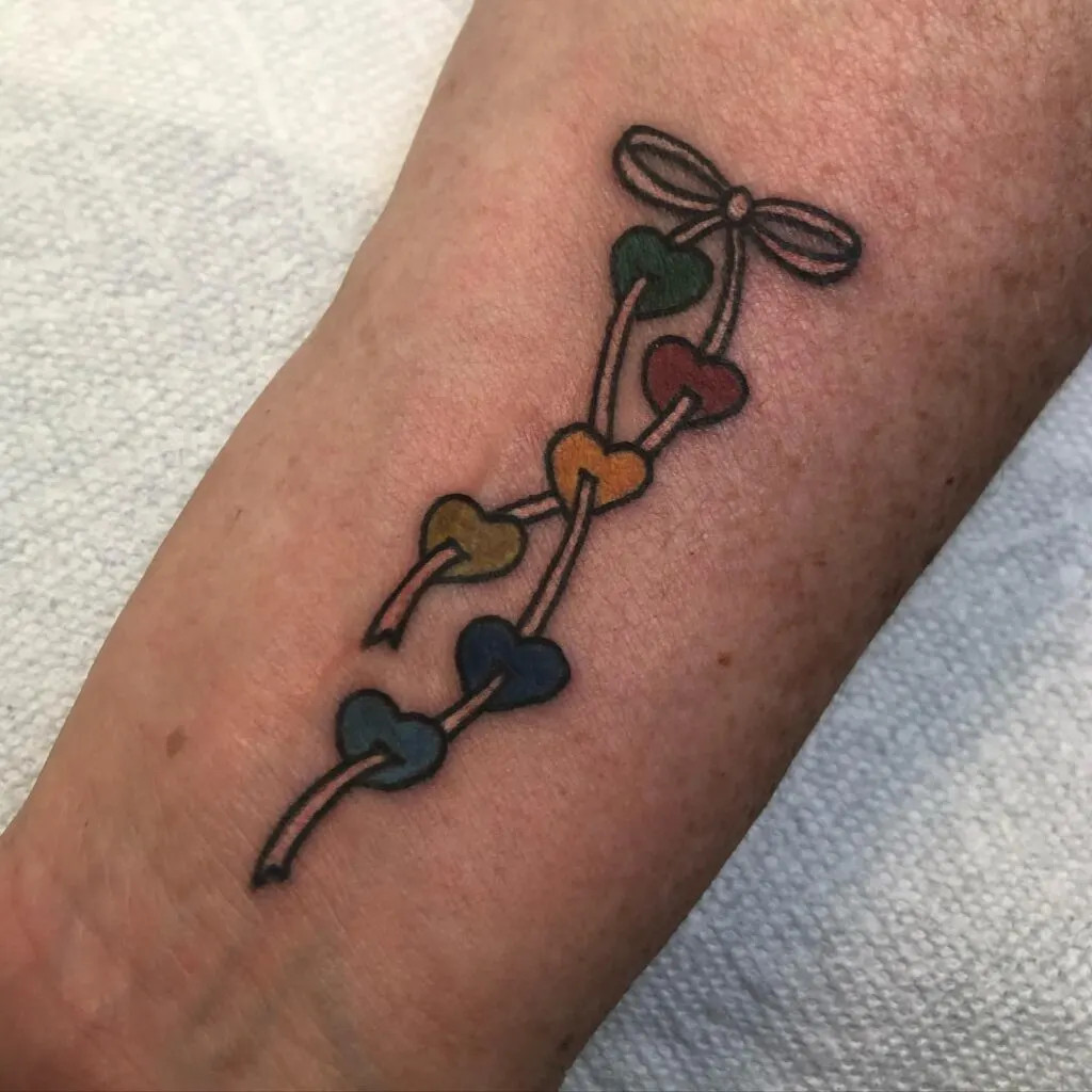 Colorful hearts connected by string tattoo, showcasing diversity and unity within the family with vibrant colors and interconnected hearts