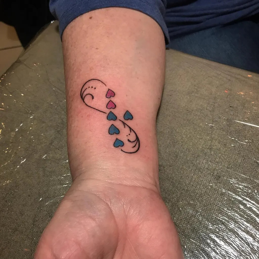Infinity symbol with hearts tattoo, symbolizing eternal love and connection with hearts in pink and blue